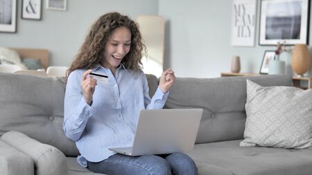 Excited Curly Hair Woman Successfully Shopping Online with Credit Cardの写真素材
