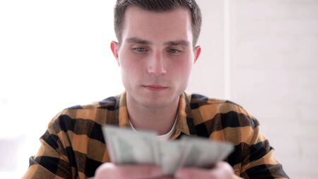 Young Man Counting Dollar Paper Currencyの写真素材