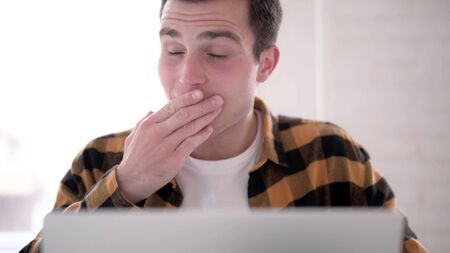 Close Up of Yawning Tired Young Man at Workの写真素材
