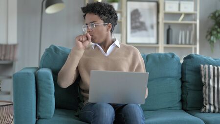 The Young African Girl Coughing while working on laptopの写真素材