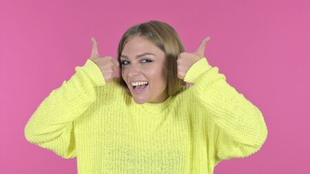 Excited Young Girl Showing Thumbs Up, Pink Backgroundの写真素材