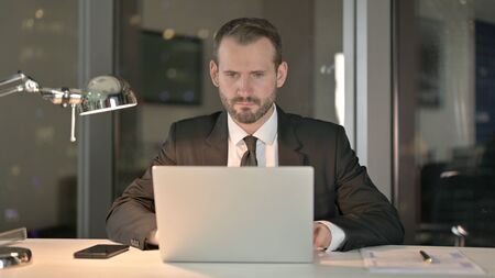 The Businessman working on Laptop in Office at Night
