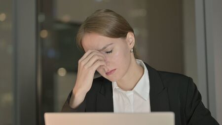 The Close Up of Tired Businesswoman having Headache in Office at Nightの写真素材