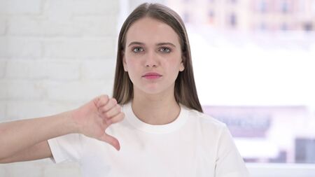 Portrait of Disappointed Young Woman doing Thumbs Down in Office