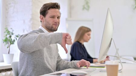 Upset Man showing Thumbs Down in Office