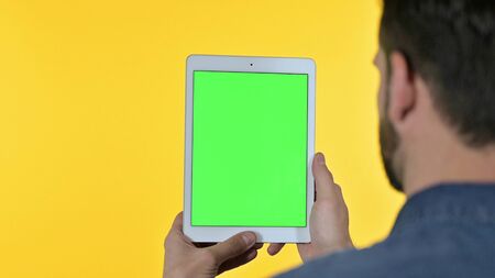 Portrait of Male Designer showing Tablet Screen with Chroma Screen, Yellow Background