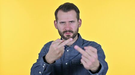Portrait of Angry Young Man Showing Middle Finger, Yellow Backgroundの写真素材
