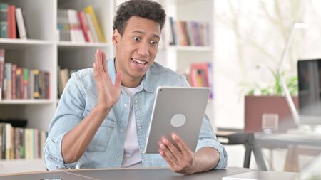 Online Video Chat on Tablet by Young African American Man at Workの写真素材