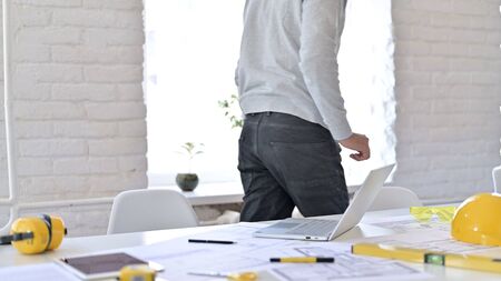Serious Young Architect Standing up Going Away at Work