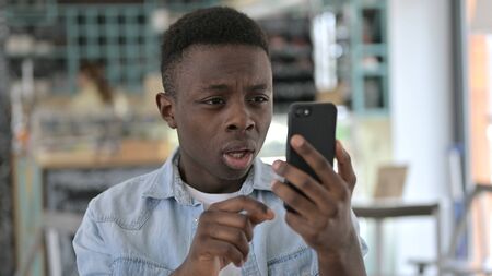 Portrait of Young African Man reacting to Failure on Smartphone
