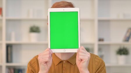 Portrait of Man holding Tablet with Chroma Screen over his Faceの写真素材