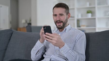 Excited Young Man surprised by Results on Smartphone