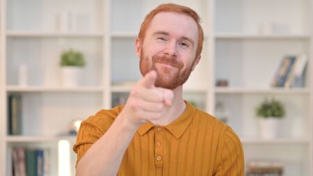 Portrait of Smiling Redhead Man Pointing at Cameraの写真素材