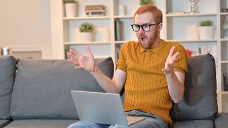 Redhead Man Reacting to Loss on Laptop at Home