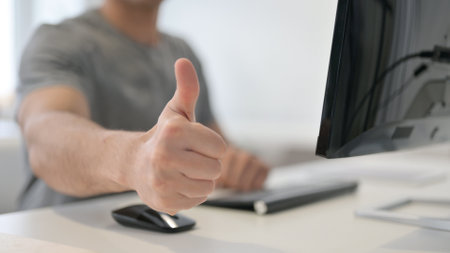 Young Man showing Thumbs up while Using Desktop, Close Upの写真素材