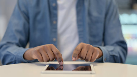 Close Up of African Man Typing on Tablet kept on Tableの写真素材