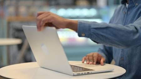 African Man Opening Laptop and Typing in Cafe, Close Up