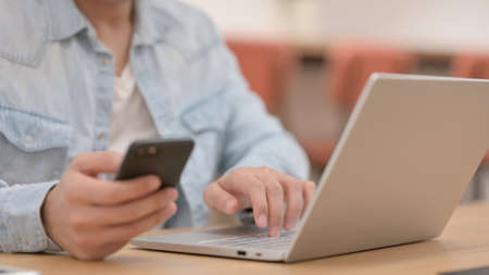 Male Hands using Smartphone while Typing on Laptop, Close up