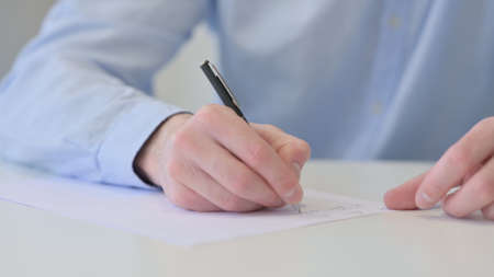 Close up of Young Man Writing on Paperの写真素材