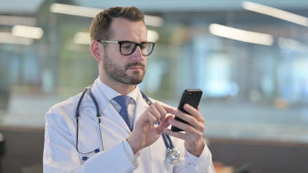 Portrait of Young Male Doctor using Smartphoneの写真素材