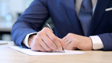 Close up of Hands of Middle Aged Businessman Writing on Paperの写真素材