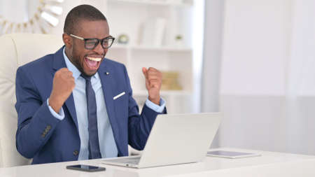 Winning, African Businessman Celebrating Success on Laptopの写真素材