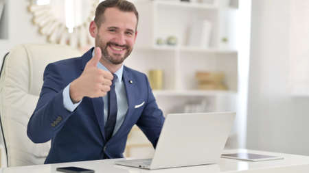 Positive Businessman with Laptop doing Thumbs Upの写真素材