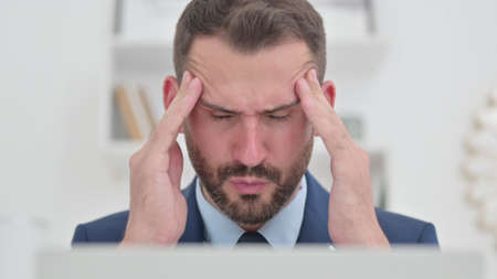 Portrait of Hardworking Businessman with Laptop having Headache