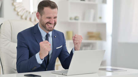 Excited Businessman Celebrating Success on Laptop in Office