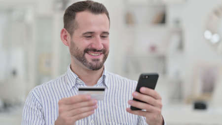 Portrait of Young Man making Online Payment on Smartphoneの写真素材
