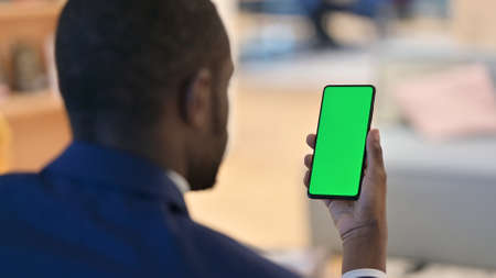 African Man Holding Smartphone with Green Chroma Screenの写真素材
