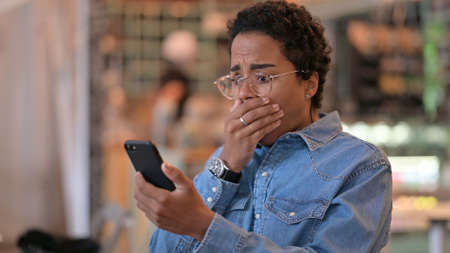 Portrait of African Woman having Loss on Smartphoneの写真素材