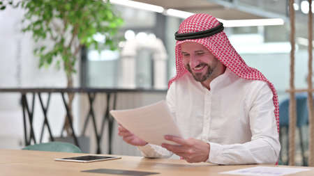 Arab Businessman Celebrating Success on Documentsの写真素材