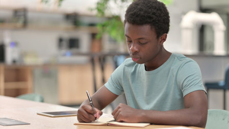 Young African Man Writing on Paperの写真素材