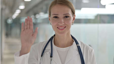 Cheerful Female Doctor Waving at the Cameraの写真素材