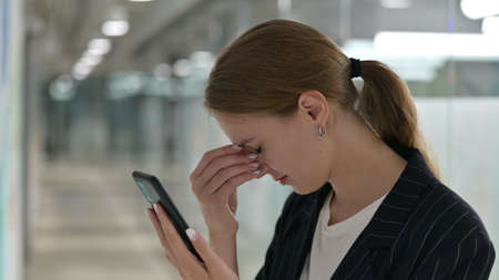 Young Businesswoman having Loss on Smartphoneの写真素材