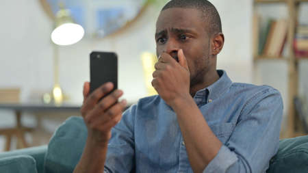 Young African Man Loss on Smartphone