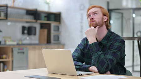 Redhead Man with Laptop Thinking in Cafe
