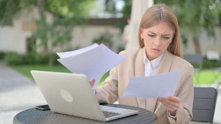 Paperwork by Businesswoman with Laptop in Outdoor Cafe