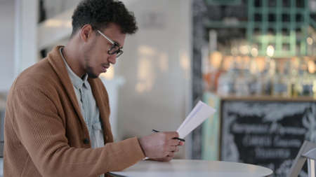 Happy African Man Reading Papers in Cafe