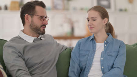 Happy Couple having Conversation while Sitting on Sofaの写真素材