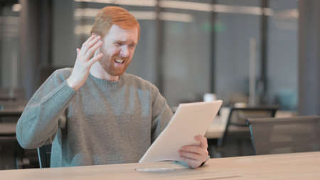 Young Man Upset while Reading Documents in Officeの写真素材