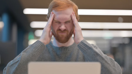Portrait of Man having Headache while using Laptopの写真素材