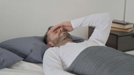Man having Headache while Sleeping in Bedの写真素材