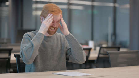 Young Man having Headache while Sitting in Officeの写真素材