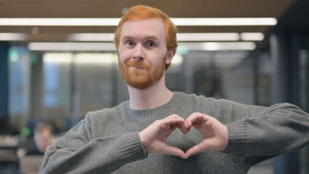 Portrait of Young Man showing Heart Shape by Handsの写真素材