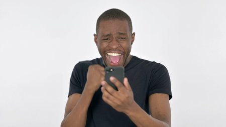 Young African Man Celebrating on Smartphone on White Backgroundの写真素材
