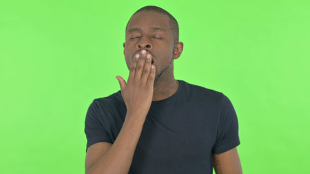 Yawning Young African Man on Green Backgroundの写真素材