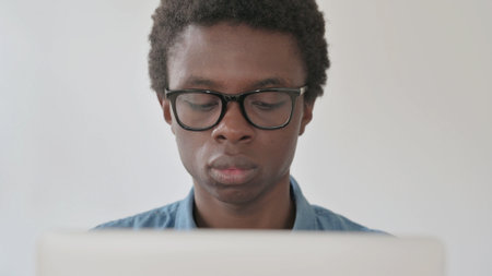 Close Up of Young African Man Using Laptop in Officeの写真素材