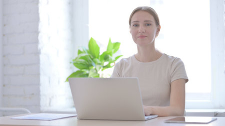 Woman Looking at Camera while using Laptopの写真素材
